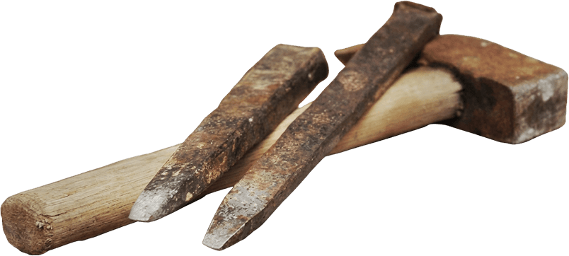 Traditional mason's chisels and hammer resting on cut stone
